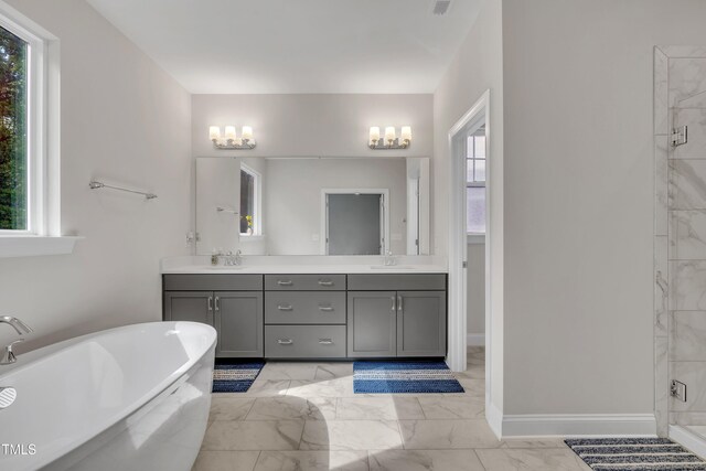bathroom featuring double vanity, a freestanding tub, a stall shower, a sink, and marble finish floor