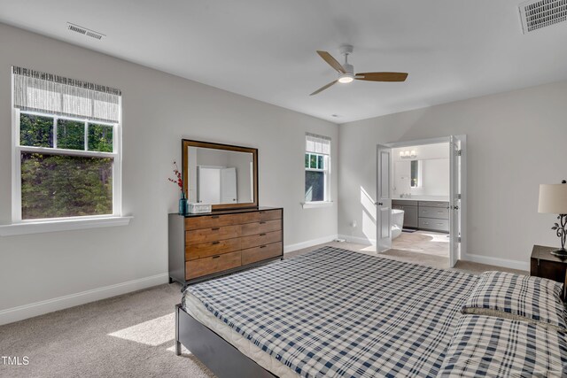 bedroom with baseboards, ensuite bathroom, light carpet, and visible vents