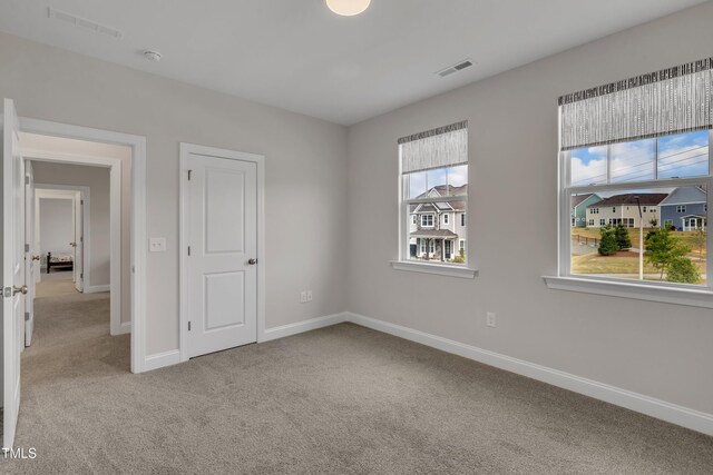 unfurnished bedroom featuring baseboards, visible vents, and carpet