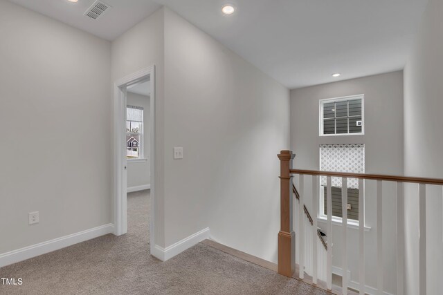 hallway with visible vents, baseboards, recessed lighting, carpet, and an upstairs landing