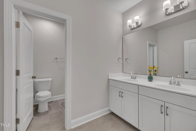 bathroom with double vanity, a sink, baseboards, and toilet