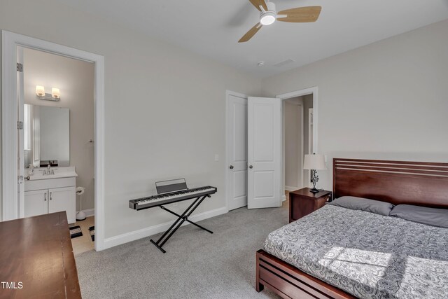 bedroom featuring a ceiling fan, a sink, baseboards, light carpet, and ensuite bath