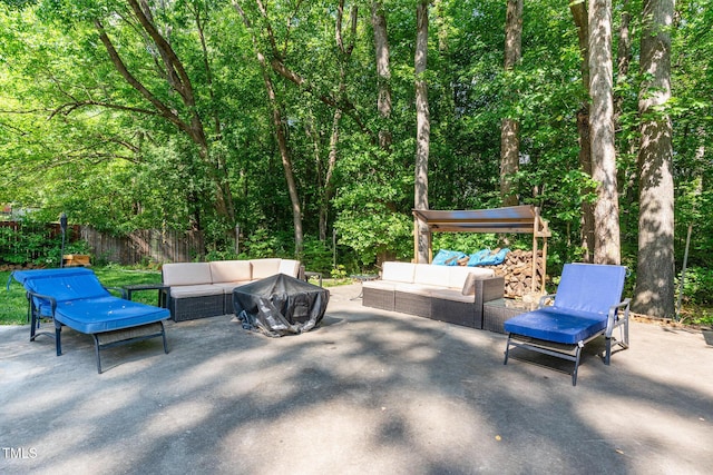 view of patio / terrace featuring fence, an outdoor living space with a fire pit, and a forest view
