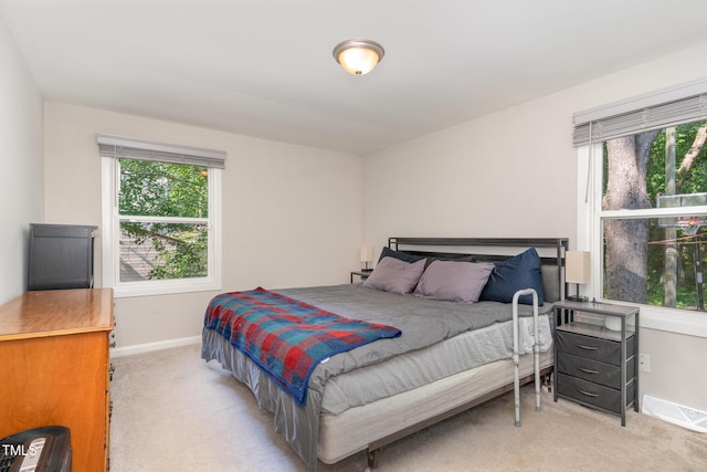 bedroom featuring baseboards, visible vents, and light carpet