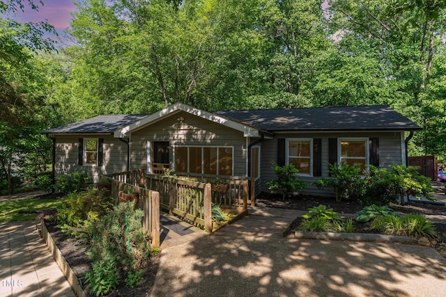 ranch-style house featuring roof with shingles and a deck