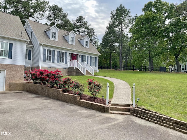 cape cod-style house with roof with shingles, fence, and a front yard