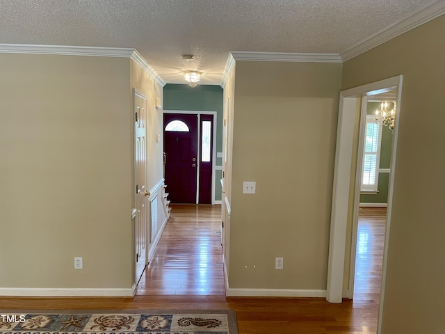 entryway with a textured ceiling, ornamental molding, baseboards, and hardwood / wood-style floors