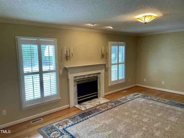 unfurnished living room featuring visible vents, a wealth of natural light, and wood finished floors