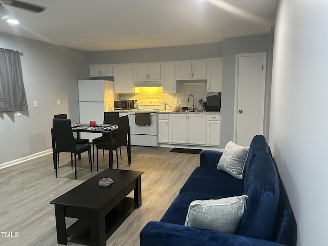 living room featuring light wood-style floors, a ceiling fan, and baseboards