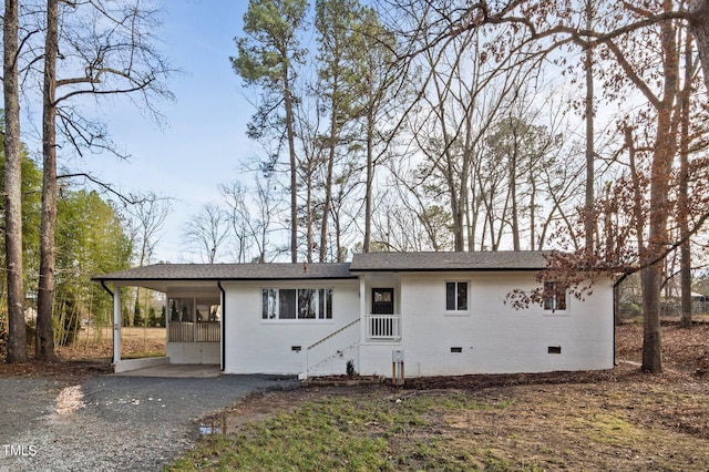 view of front of house with crawl space, driveway, a carport, brick siding, and a shingled roof
