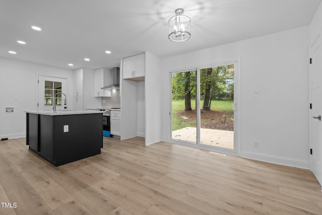 kitchen featuring light wood-style flooring, wall chimney exhaust hood, and stainless steel electric stove