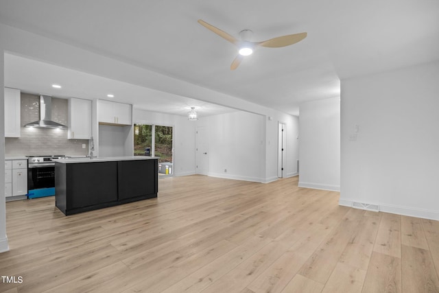 unfurnished living room featuring visible vents, a sink, baseboards, a ceiling fan, and light wood-style flooring