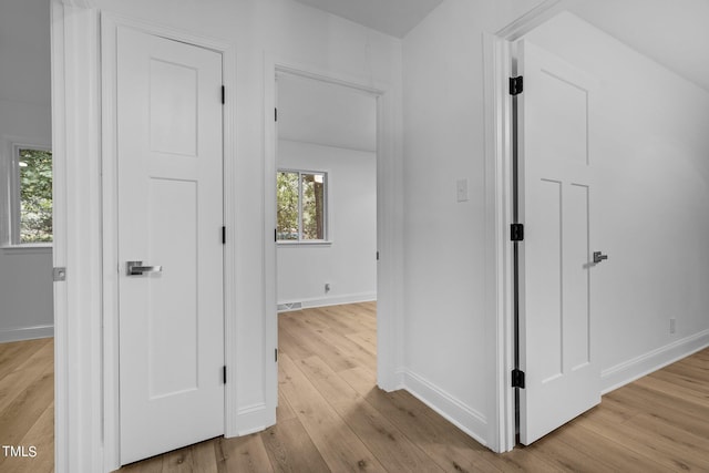 hallway with baseboards, wood finished floors, and visible vents