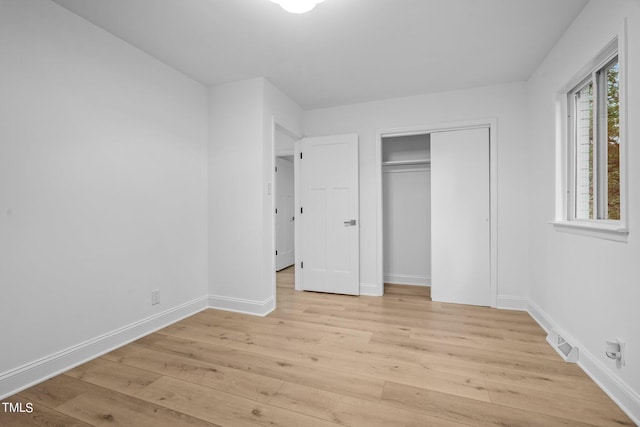 unfurnished bedroom with visible vents, baseboards, a closet, and light wood-type flooring