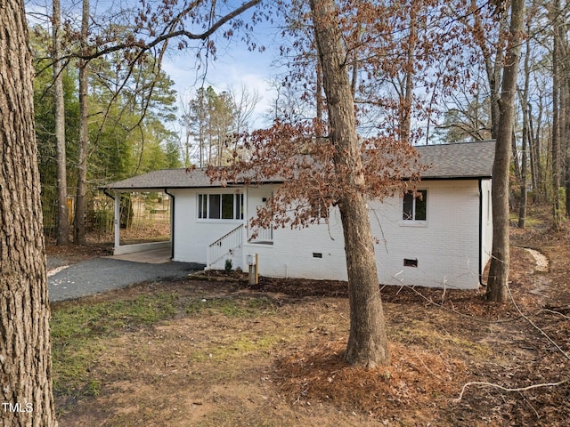 back of property with crawl space, driveway, brick siding, a shingled roof, and an attached carport