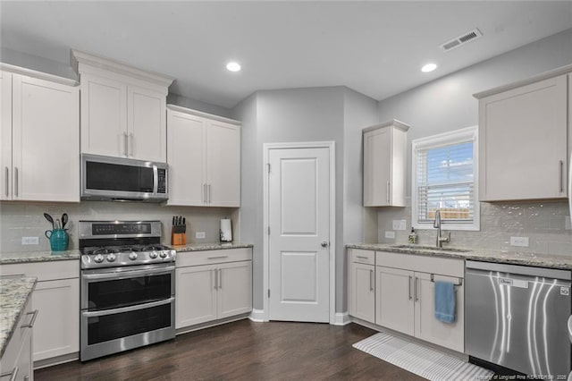 5113 Boxcut Ln, Hope Mills, NC 28348 - kitchen featuring appliances with stainless steel finishes, a sink, dark wood-style floors, white cabinetry, and decorative backsplash