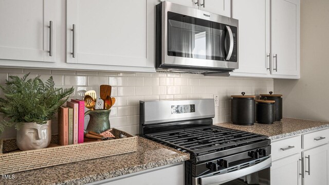 196 Ethel Ln, Angier, NC 27501 - kitchen featuring appliances with stainless steel finishes, tasteful backsplash, light stone countertops, and white cabinetry