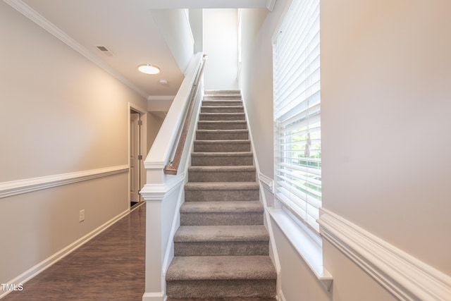 stairway with baseboards, visible vents, ornamental molding, and wood finished floors