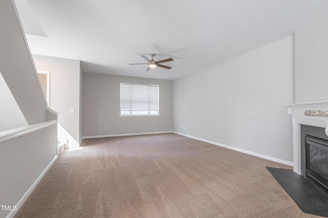 unfurnished living room featuring baseboards, a fireplace with flush hearth, a ceiling fan, and carpet flooring
