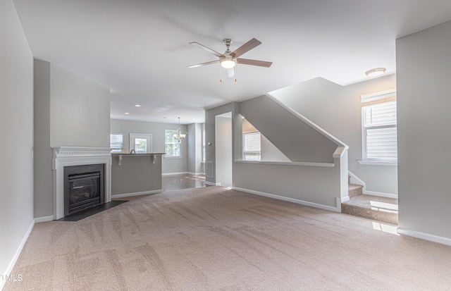 unfurnished living room with stairway, baseboards, ceiling fan, and carpet flooring