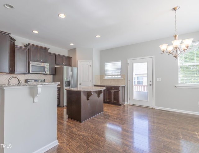 kitchen with a breakfast bar area, backsplash, dark brown cabinets, and stainless steel appliances