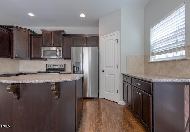 kitchen featuring decorative backsplash, dark wood finished floors, appliances with stainless steel finishes, and dark brown cabinets