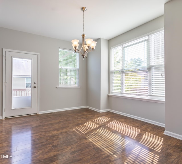 empty room featuring baseboards, visible vents, wood finished floors, and a notable chandelier