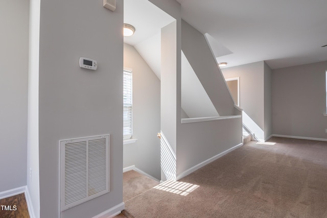 corridor featuring baseboards, carpet, vaulted ceiling, and visible vents