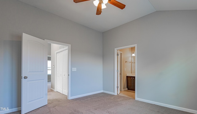 unfurnished bedroom featuring carpet floors, lofted ceiling, baseboards, connected bathroom, and a ceiling fan