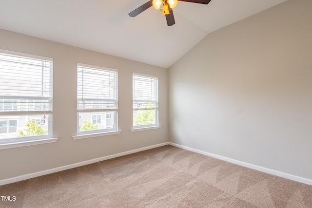 spare room with vaulted ceiling, baseboards, a ceiling fan, and light colored carpet