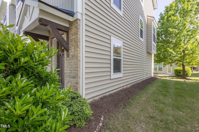 view of property exterior with a yard and brick siding
