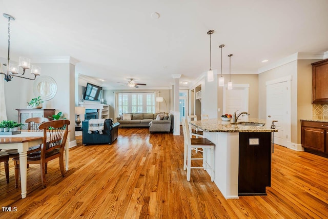 281 N Serenity Hill Cir, Chapel Hill, NC 27516 - kitchen featuring a sink, light wood-type flooring, a ceiling fan, crown molding, and light stone countertops