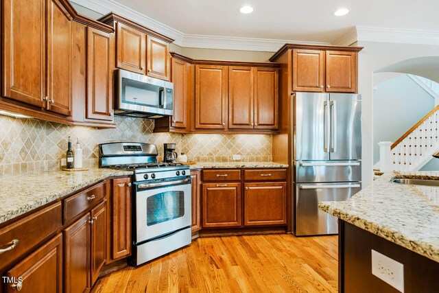 281 N Serenity Hill Cir, Chapel Hill, NC 27516 - kitchen featuring appliances with stainless steel finishes, crown molding, arched walkways, light stone counters, and brown cabinets