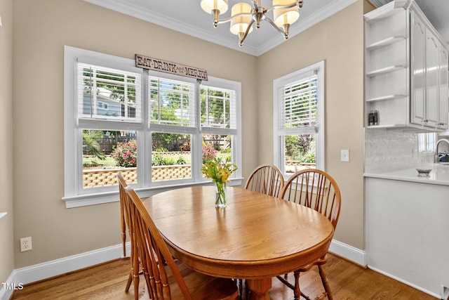 dining space with baseboards, a notable chandelier, ornamental molding, and light wood-style floors