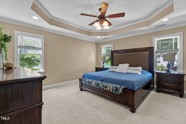 bedroom with visible vents, crown molding, light colored carpet, a raised ceiling, and baseboards