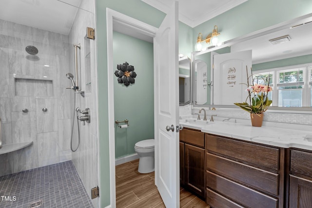 full bath featuring toilet, visible vents, a tile shower, and wood finished floors