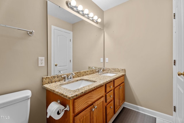 bathroom featuring double vanity, a sink, baseboards, and toilet
