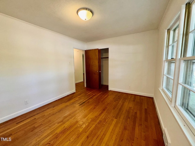 1713 S Garnett St, Henderson, NC 27536 - unfurnished bedroom featuring wood finished floors, baseboards, a closet, and multiple windows