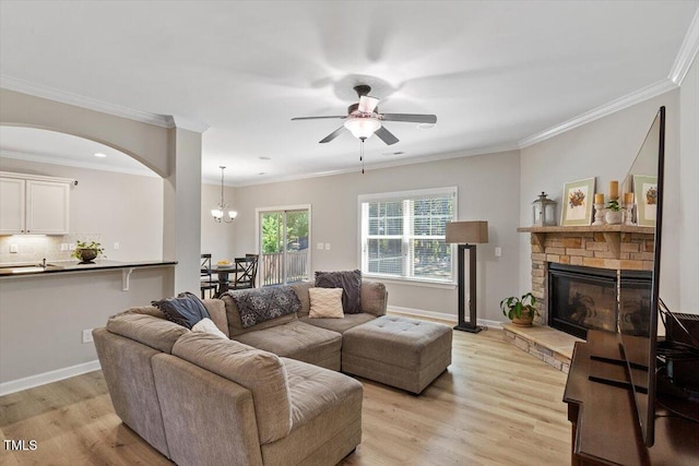 105 Blue Prince Trl, Holly Springs, NC 27540 - living area featuring ceiling fan, a stone fireplace, light wood-style floors, arched walkways, and ornamental molding