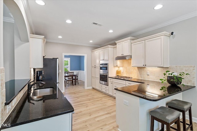 105 Blue Prince Trl, Holly Springs, NC 27540 - kitchen featuring ornamental molding, a sink, light wood-type flooring, under cabinet range hood, and a peninsula