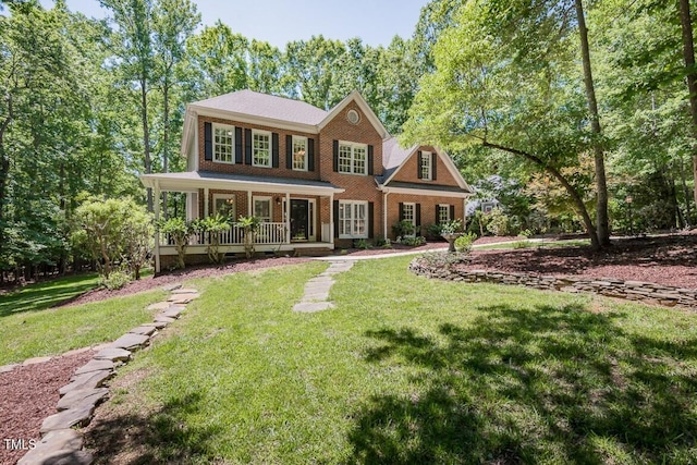 view of front of property with brick siding, a front yard, and covered porch
