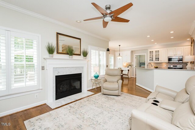 living room featuring ornamental molding, plenty of natural light, wood finished floors, a ceiling fan, and recessed lighting