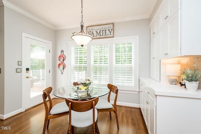 dining area with wood finished floors, healthy amount of natural light, crown molding, and baseboards