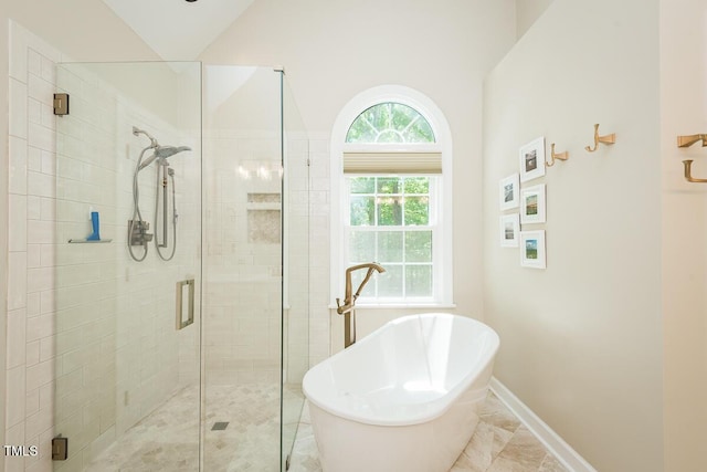 full bath featuring a shower stall, a freestanding tub, and baseboards