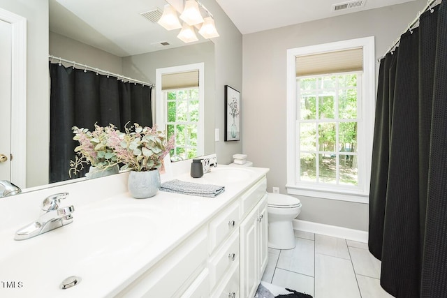 bathroom featuring toilet, double vanity, tile patterned flooring, and baseboards