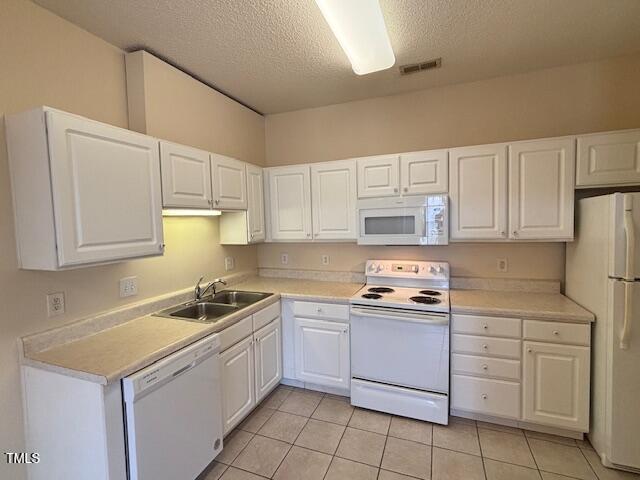 kitchen featuring white appliances, white cabinetry, and a sink