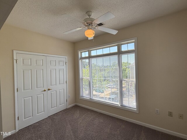 unfurnished bedroom with a closet, baseboards, ceiling fan, a textured ceiling, and carpet flooring