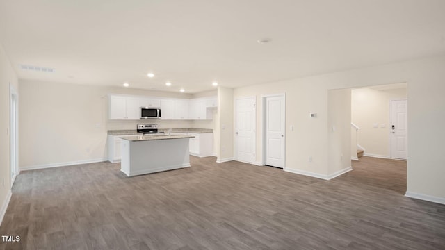 kitchen with baseboards, open floor plan, a center island with sink, recessed lighting, and appliances with stainless steel finishes
