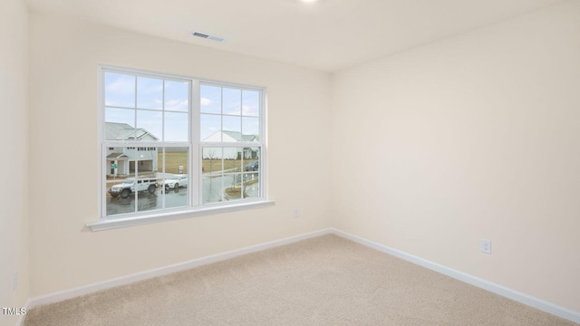 carpeted spare room featuring baseboards and visible vents