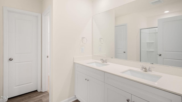bathroom featuring double vanity, visible vents, a sink, and wood finished floors